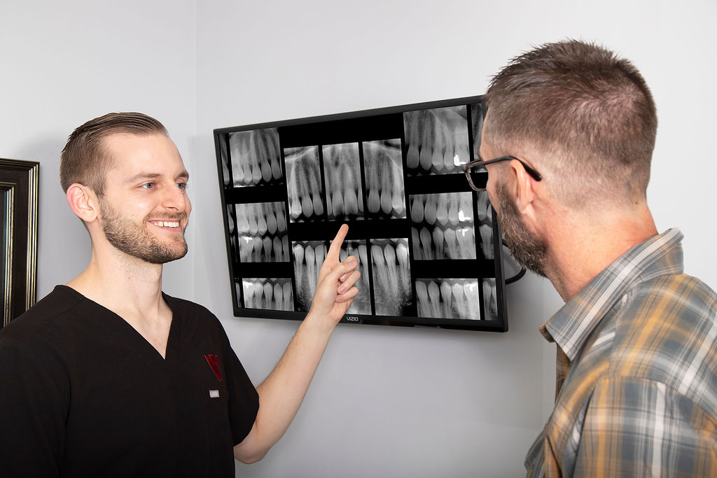 Dr. Fischman points to a dental x-ray on a monitor while speaking to a dental patient