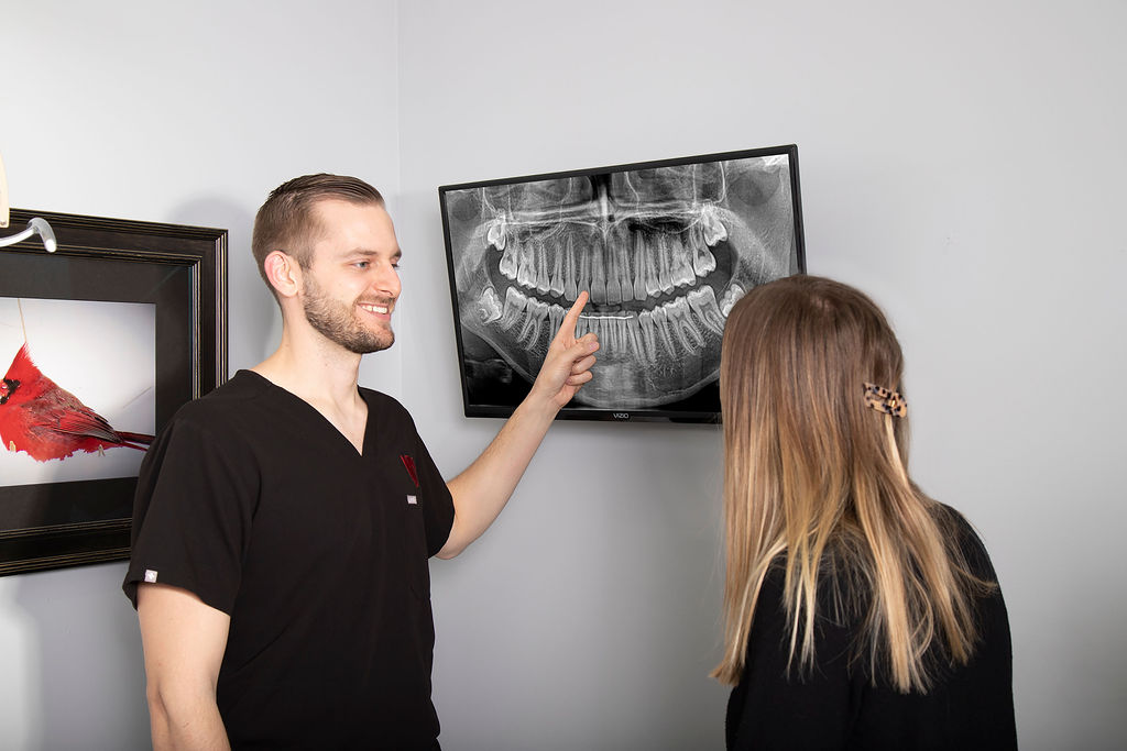 Dr. Fischman points to a dental x-ray on a monitor while speaking to a dental patient